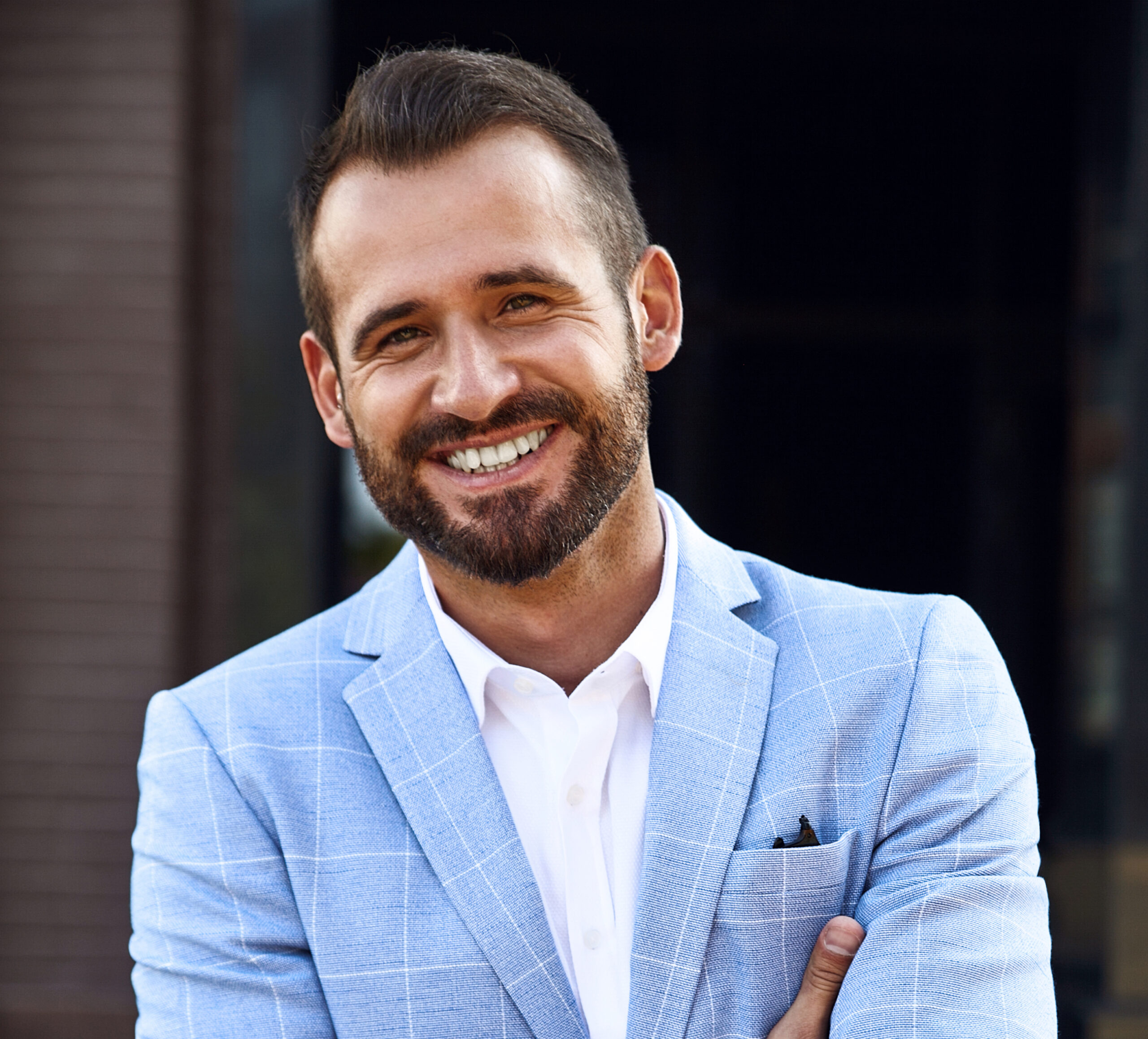 portrait of sexy handsome fashion businessman model dressed in elegant blue suit posing on street background. metrosexual